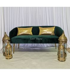 a green velvet couch with gold pillows and lanterns