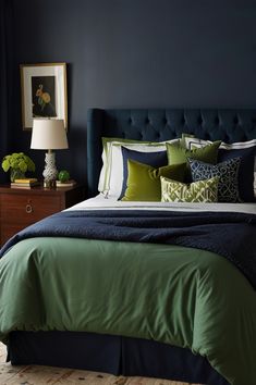 a bedroom with dark blue walls and green bedding