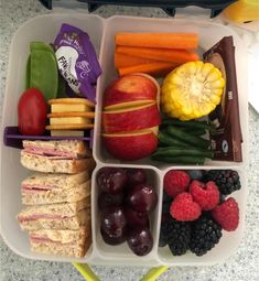 a lunch box filled with fruits, vegetables and crackers on top of a table