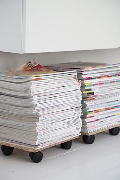 several stacks of magazines sitting on top of each other in front of a white cabinet