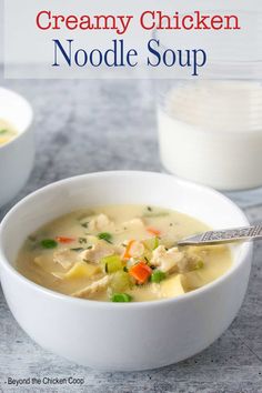 creamy chicken noodle soup in a white bowl with a spoon and glass of milk