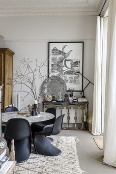 an elegant dining room with black chairs and white rugs, artwork on the wall