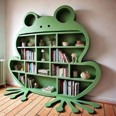 a green frog shaped bookcase with books on it's sides and shelves filled with books