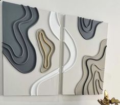 two abstract paintings on the wall next to a vase with gold and silver flowers in it