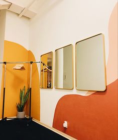 a room with three mirrors on the wall and a potted plant next to it