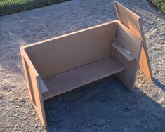 a wooden bench sitting in the middle of a dirt field next to grass and bushes