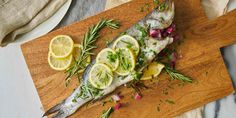 fish with herbs and lemons on a wooden cutting board