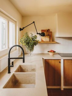 a kitchen with a sink, counter top and window above it that has flowers in a vase