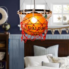 a lamp hanging from the ceiling in a room with blue walls and white bedding