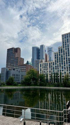 the city skyline is reflected in the still water of this lake on a partly cloudy day