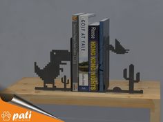 three bookends made out of pixellated books on a wooden table with grey background