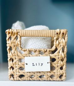 a wicker basket with a label that says lilly on it, sitting on a table