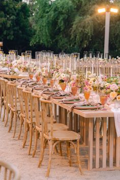 a long table set up with flowers and candles for an outdoor wedding reception in the sand