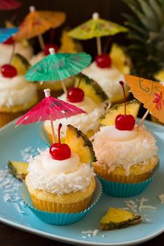 pineapple cupcakes with white frosting and cherries topped with umbrellas