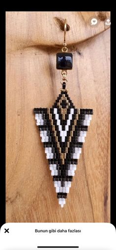 a black and white beaded triangle hanging from a wooden wall