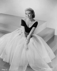 a woman in a black and white dress sitting on stairs with her hands on her hips