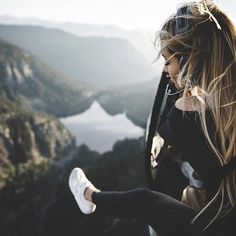 a woman sitting in the back of a helicopter looking out over a mountain valley and lake