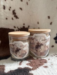 two glass jars sitting on top of a cow print rug