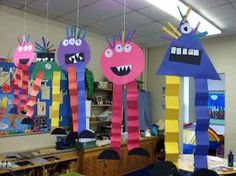 some very colorful paper monsters hanging from the ceiling in an art class or school room