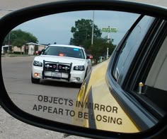 a police car is seen in the rear view mirror