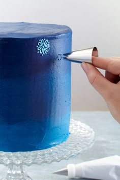 a person is decorating a blue cake with icing