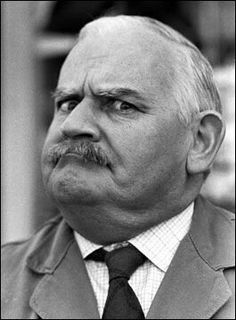 an older man with a mustache wearing a suit and tie, looking off to the side