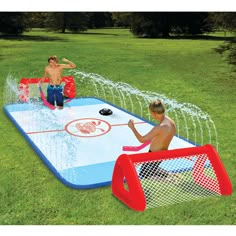 an inflatable water table with two kids playing on it and sprinklers