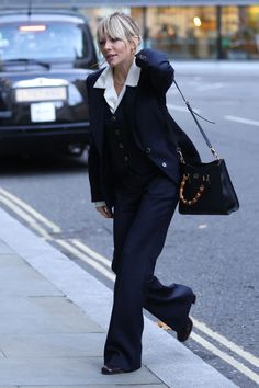 a woman walking down the street carrying a purse