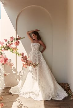 a woman in a wedding dress leaning against a wall with her hand on her head