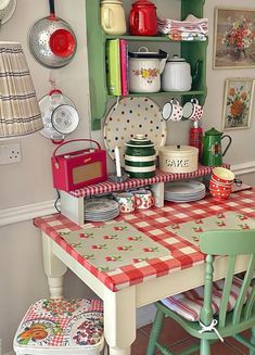 a kitchen with green cabinets and red checkered table cloth on the dining room table