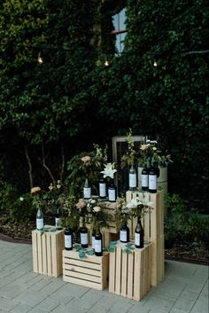 several wine bottles are stacked on wooden crates with flowers and greenery in the background