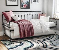 a bed with white sheets and red pillows on top of it, next to a window