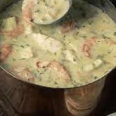 a pot filled with shrimp and cheese soup on top of a wooden table