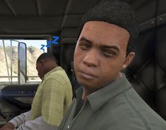 two men are sitting in the driver's seat of a vehicle and one man is looking at the camera