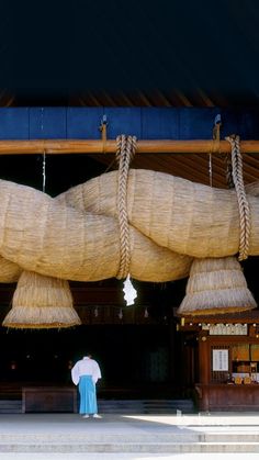 a man standing in front of a building with large rafters hanging from it's ceiling