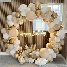 a happy birthday balloon arch with white and gold balloons, pineapples and palm leaves