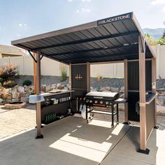 an outdoor bbq with grills and barbecue tables under a covered area in the back yard