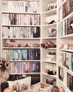 a bookshelf filled with lots of books next to a vase and pumpkins