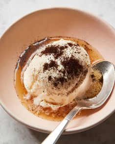 a bowl filled with ice cream on top of a white table next to a spoon