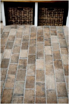 two wicker baskets sitting on top of a tiled floor next to a wooden table