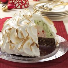 a cake with white frosting on a silver plate and red place mat next to it