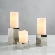 three lit candles sitting on top of a white table next to each other with one candle in the middle