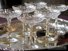 there are many wine glasses on the silver platter with gold rims and one is empty