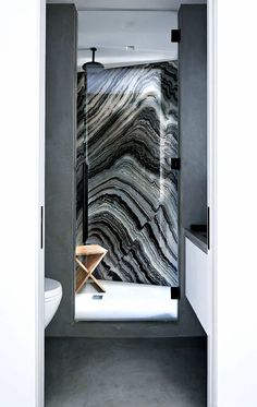 an open door leading to a bathroom with black and white marble on the shower wall