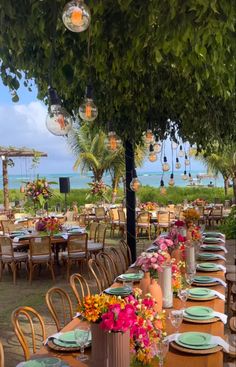 an outdoor dining area with tables, chairs and vases filled with flowers on each table