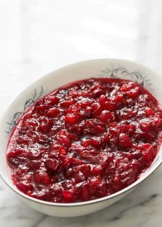 a white bowl filled with cranberry sauce on top of a marble counter