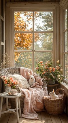 a white rabbit sitting on top of a chair in front of a window next to a basket filled with flowers