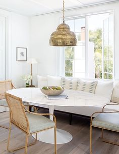 a living room with white couches and chairs in front of a large round table