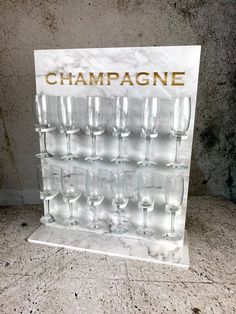 champagne glasses are lined up in front of a white marble display case that says champagne