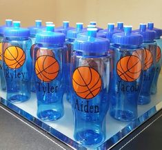 blue water bottles with orange basketballs on them are sitting on a table in front of a mirror